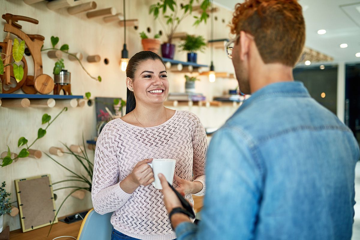 A PS&D recruiter, a white man, in a coffee shop with a physician, a Hispanic woman, discussing career, both casually dressed.